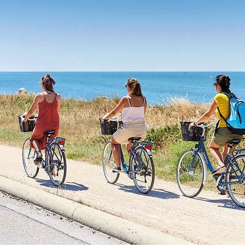 Trois femmes à vlo sur une piste cyclable longeant la plage près de la Baule
