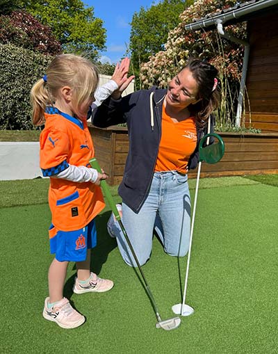 Little girl and her mother playing golf on the putting green of the campsite near La Baule